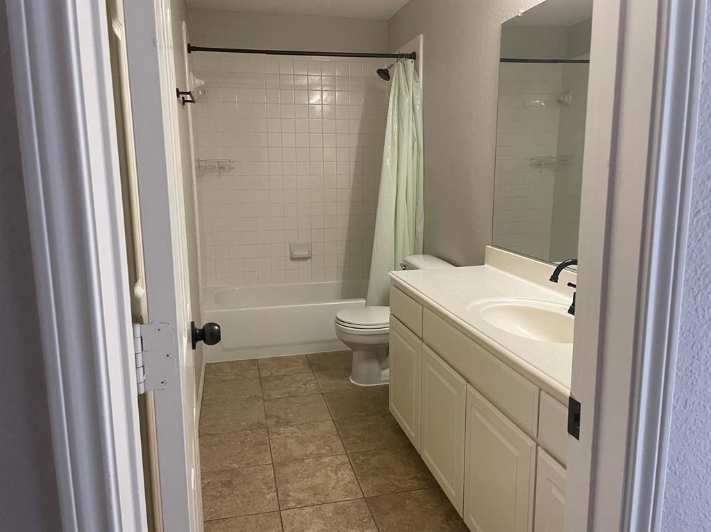 Full bathroom featuring a vanity with an integrated basin, wall-to-wall mirror, tiled flooring, and a tub-shower combination with tile surround