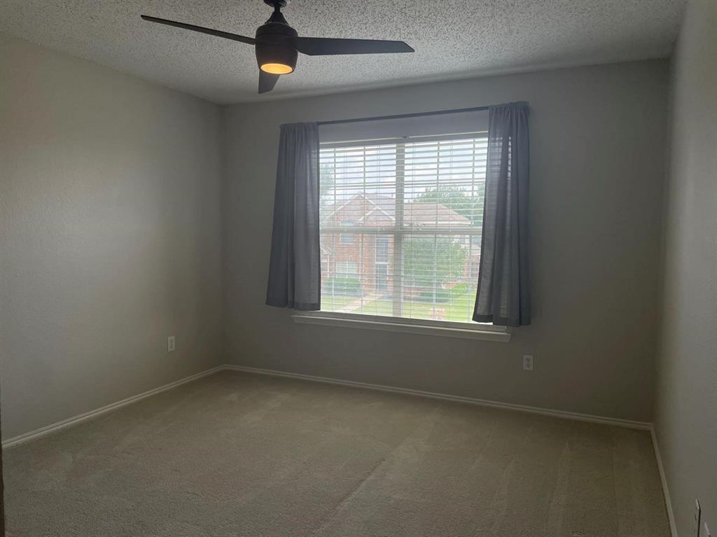 Neutral-toned walls, plush wall-to-wall carpeting, large window with integrated blinds, and a modern ceiling fan with light fixture