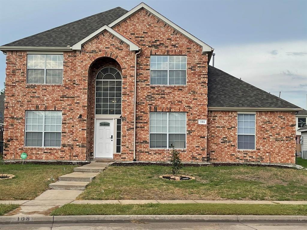 Two-story brick exterior featuring a multi-gabled roofline, an arched entryway with a palladium window, and a concrete walkway