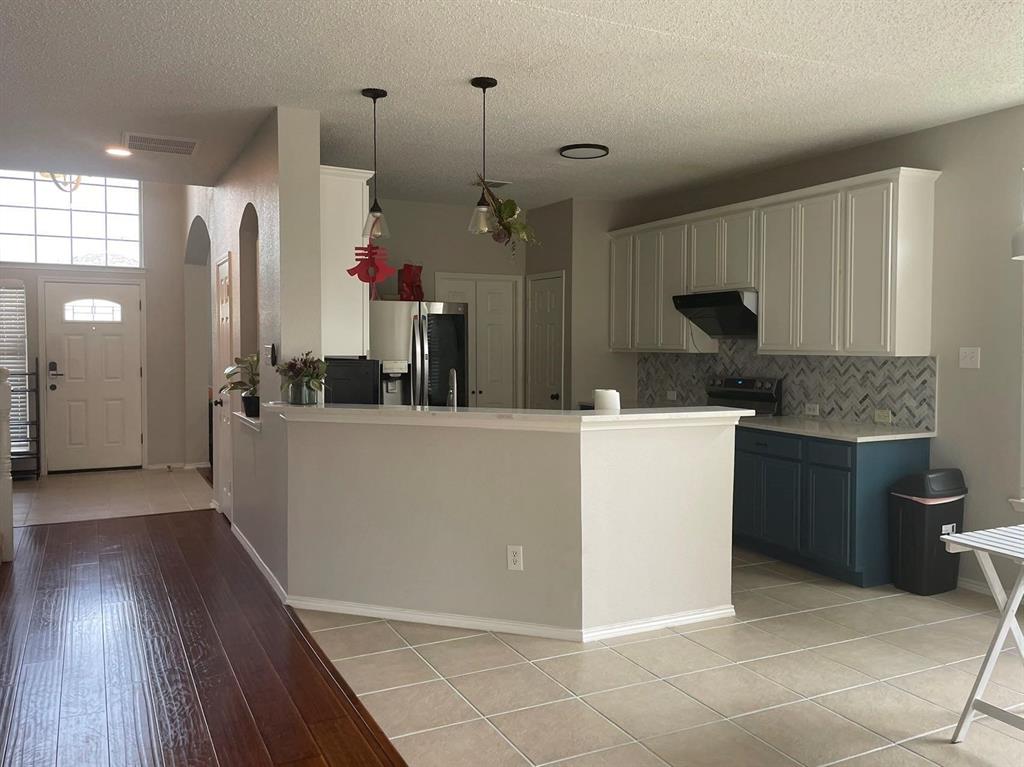 Kitchen featuring two-tone cabinetry, herringbone tile backsplash, wood-finish flooring, and a breakfast bar with dual pendant lighting