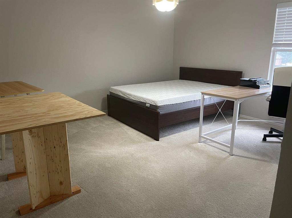 Neutral-toned interior room featuring wall-to-wall carpeting and a window with horizontal blinds