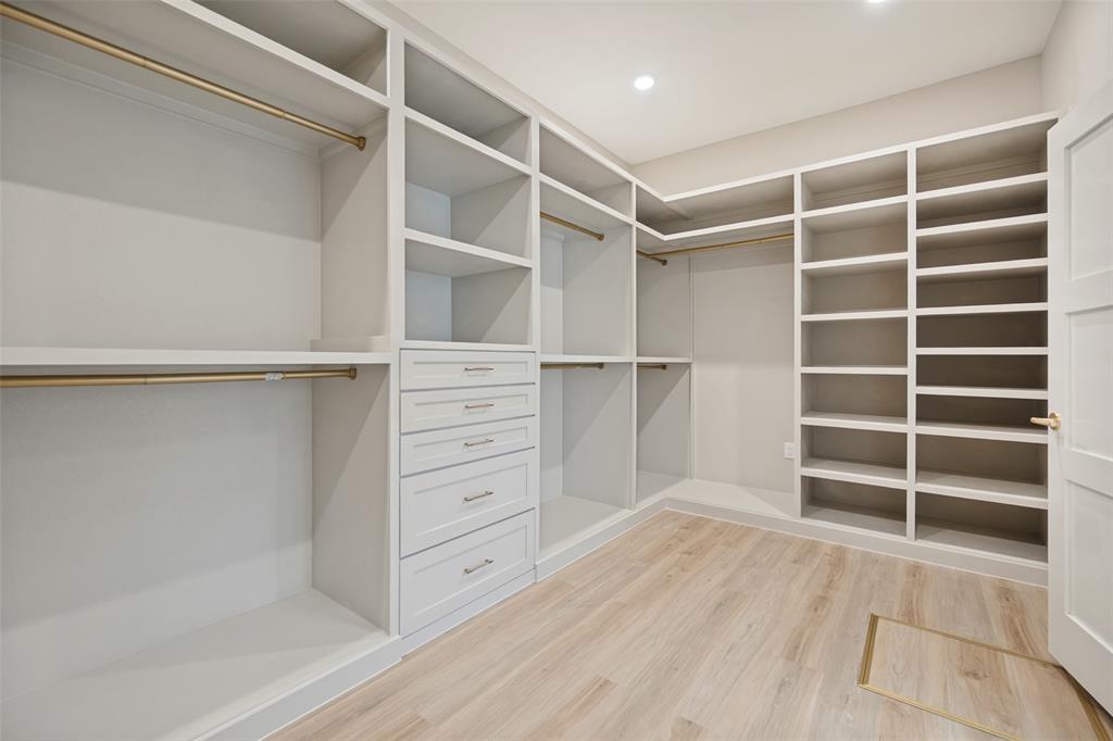 Built-in custom cabinetry with shelving, drawer storage, hanging rods, and wood-finish flooring