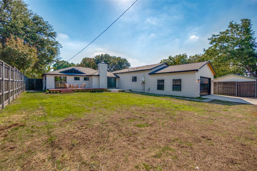 Expansive backyard with a wooden fence, detached covered parking, and a private wooden deck