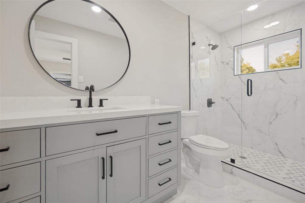 Floating vanity with a quartz countertop, circular mirror, and matte black fixtures