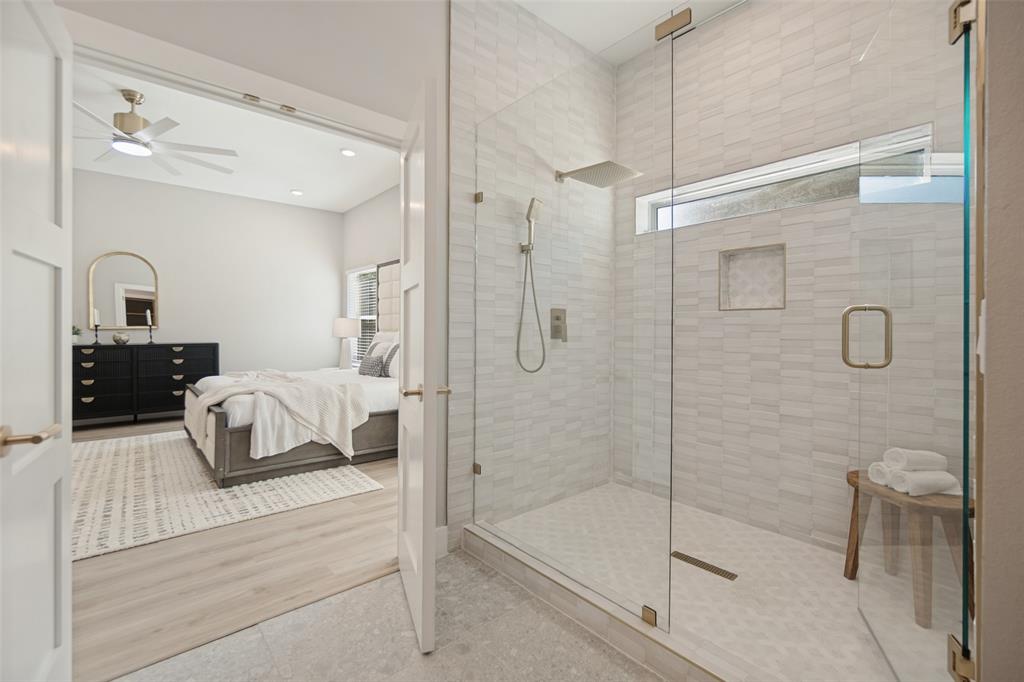 Frameless glass shower enclosure with a rain shower head, hand-held shower, and built-in niche
