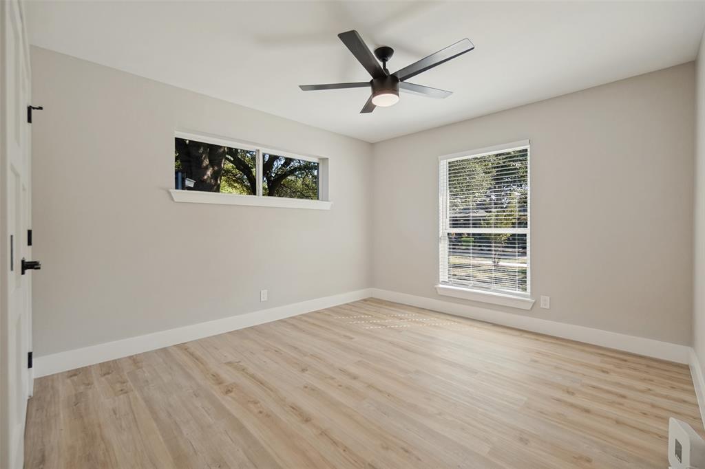 Light wood-finish flooring, overhead ceiling fan with lighting, and multiple windows