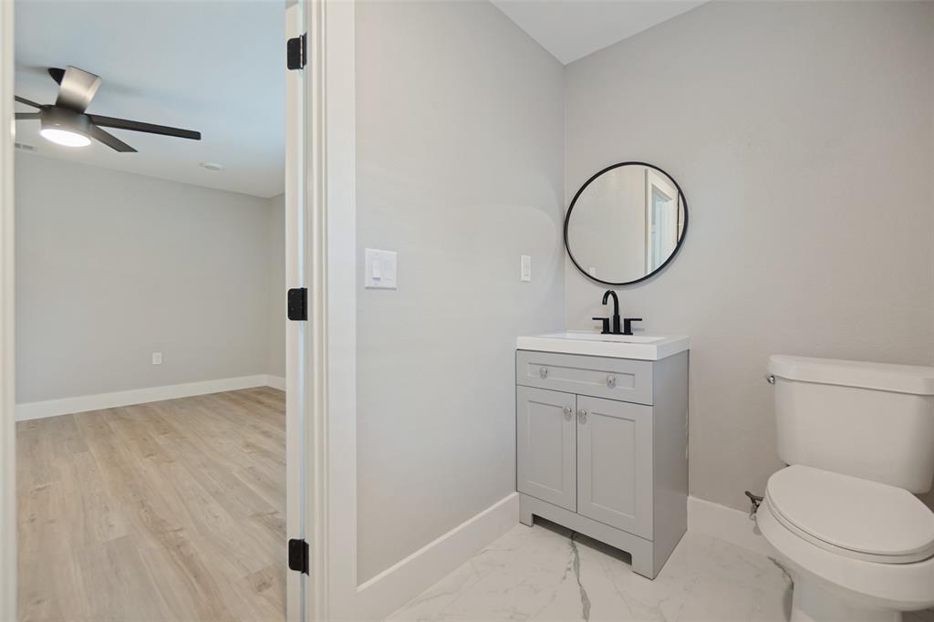Light gray vanity with an integrated sink, matte black faucet, and a round black-framed mirror