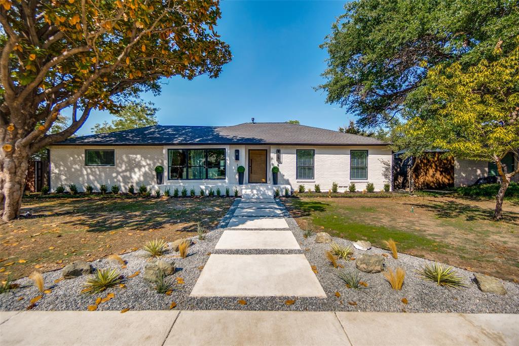 White brick exterior with a dark roof and large dark-framed windows