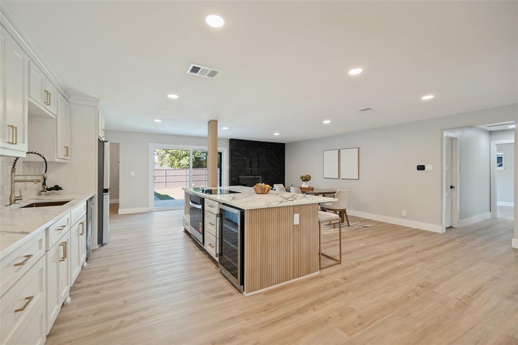 Open-concept living space with light wood-finish flooring, recessed lighting, and white cabinetry