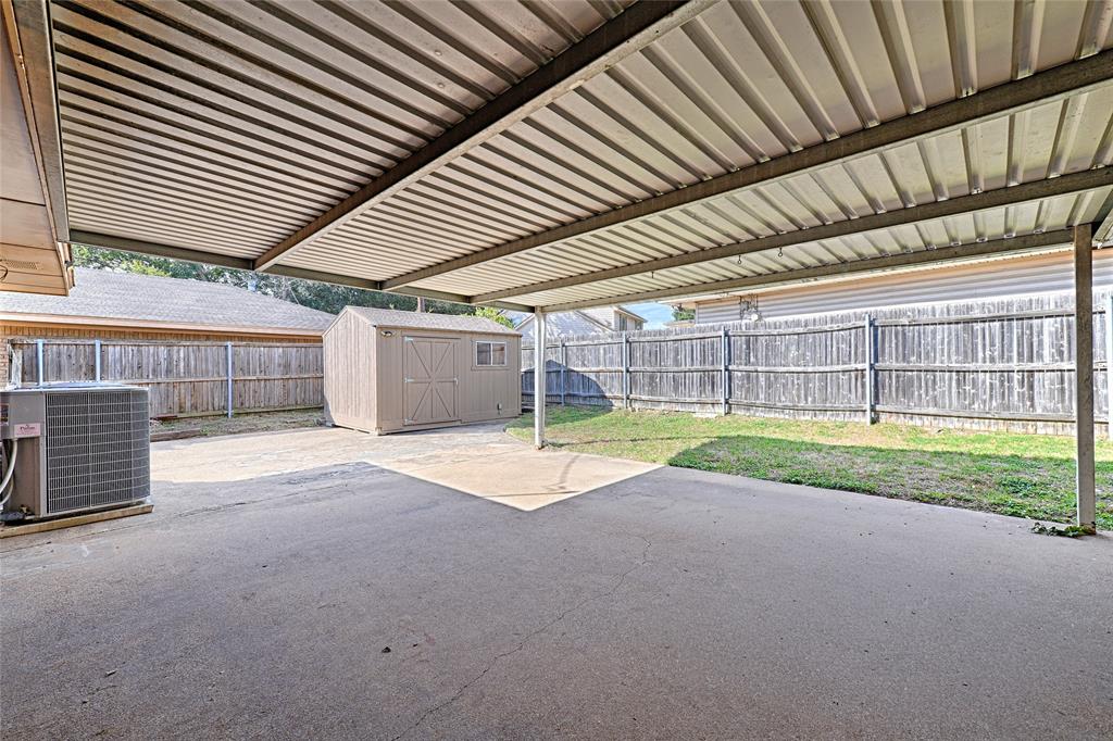 Covered concrete patio with a metal roof, exterior storage shed, and fenced backyard