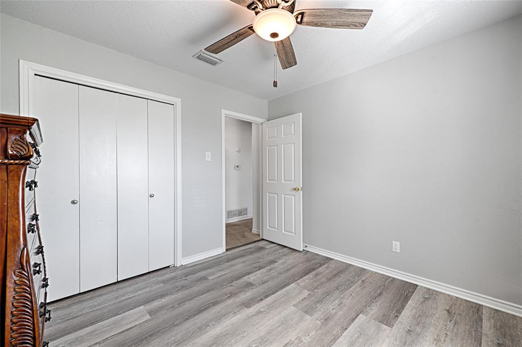 Wood-finish flooring, ceiling fan with integrated light fixture, and white six-panel interior door