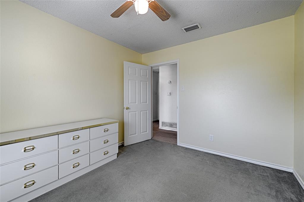 Room featuring neutral wall tones, gray carpeting, a multi-panel interior door, and a ceiling-mounted light fixture with a fan