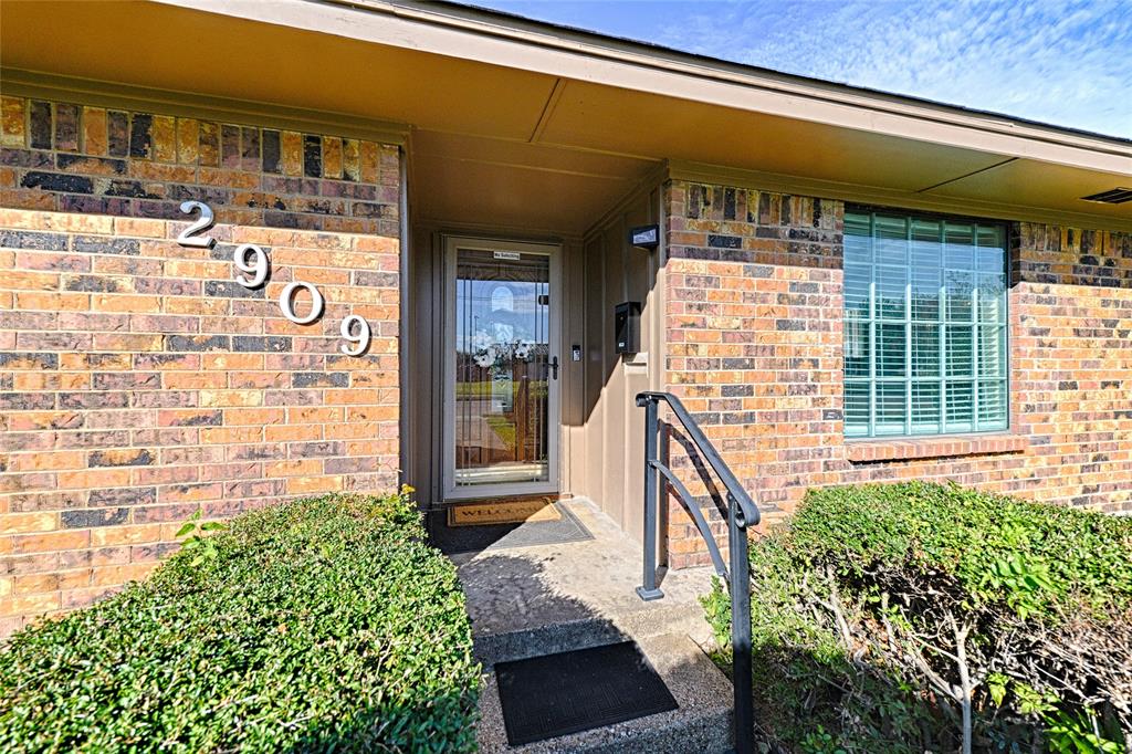 Multi-tonal brick exterior, covered entryway with concrete steps, metal handrail, and storm door with glass insert Multi-tonal brick exterior, covered entryway with concrete steps, metal handrail, and storm door with glass insert