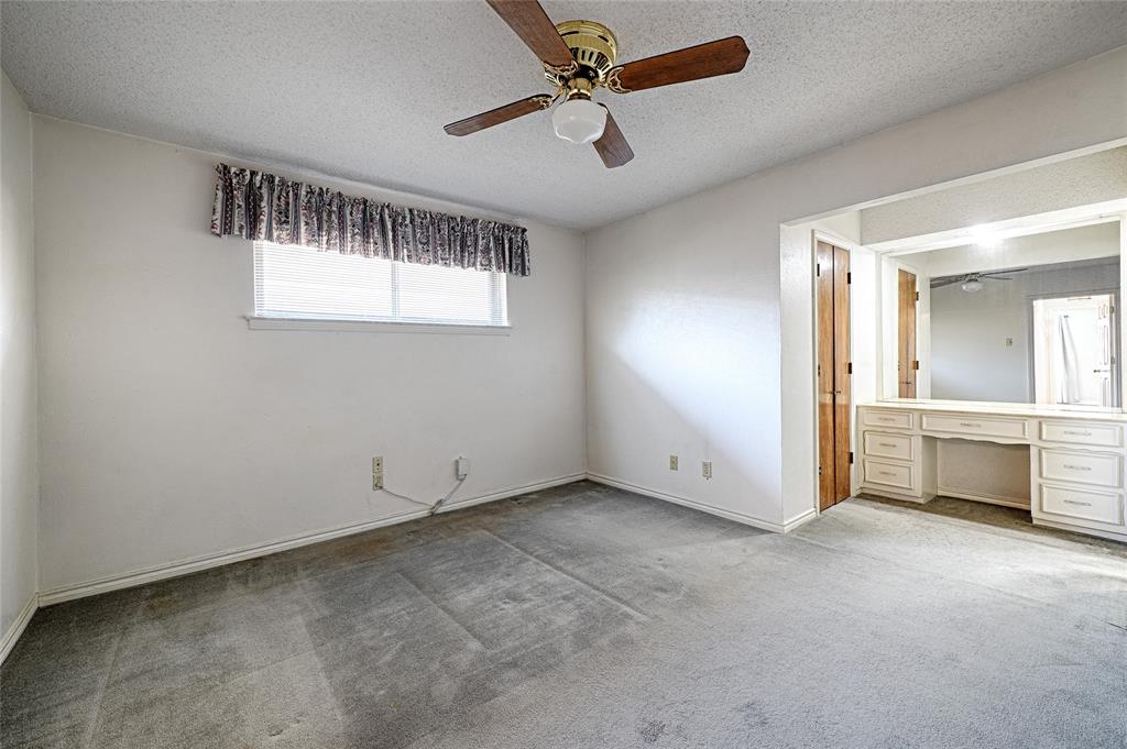 Room featuring a ceiling fan with wooden blades, wall-to-wall carpeting, and built-in cabinetry with an integrated vanity mirror