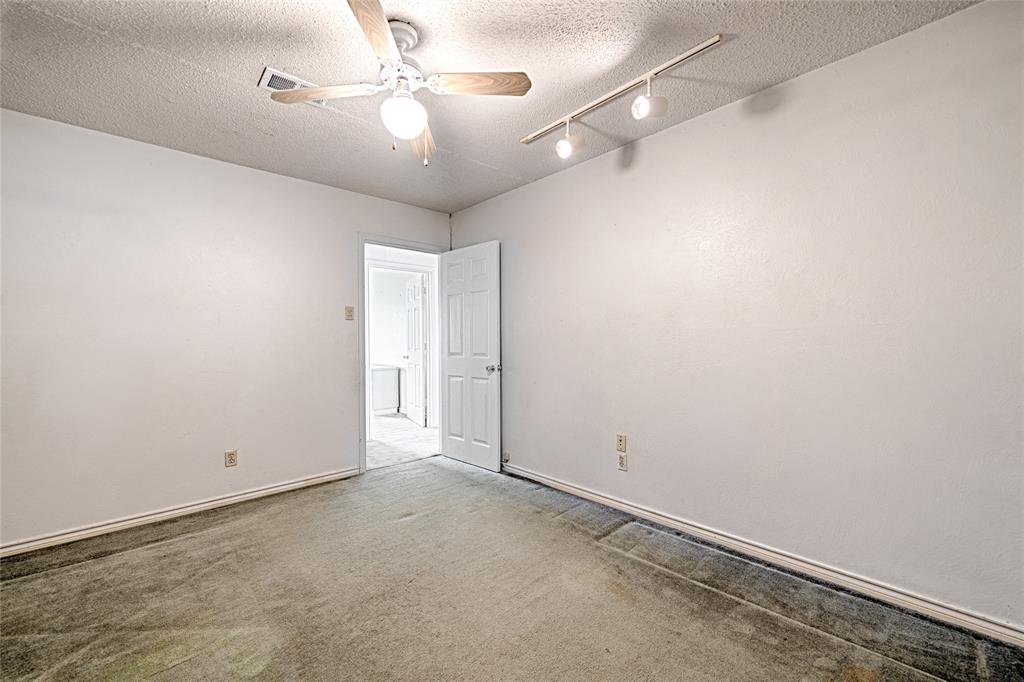 Interior space featuring neutral wall tones, carpeted flooring, a ceiling fan with integrated lighting, and adjustable multi-light track lighting