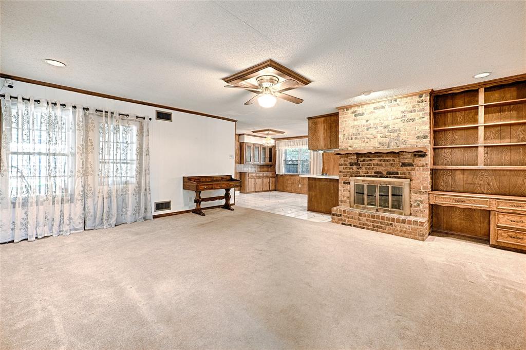 Living space featuring a brick fireplace with a wood mantel, built-in wooden shelving, recessed lighting, and a ceiling fan
