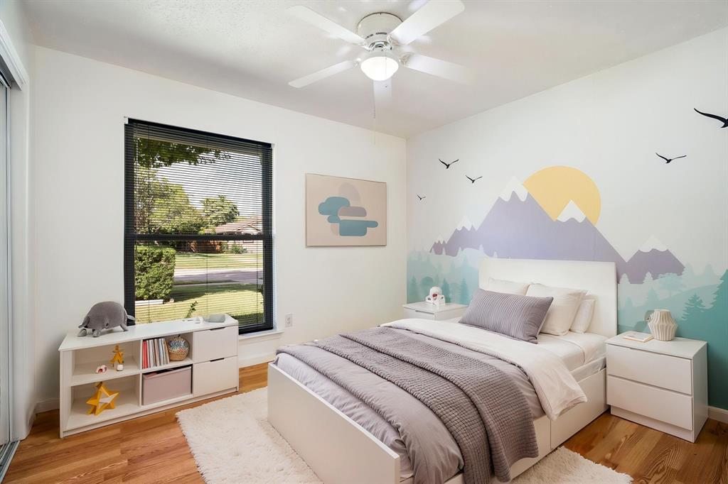 Bedroom featuring wood-finish flooring, a ceiling fan with integrated lighting, and a large window with a dark frame
