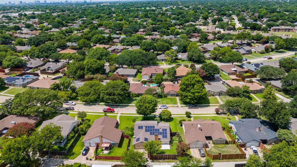 Mature tree-lined streets, residential neighborhood setting, single-story homes, and a distant urban skyline