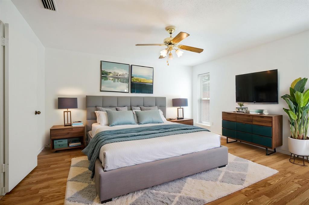 Bedroom featuring wood-finish flooring, a multi-blade ceiling fan with integrated lighting, and a vertical window