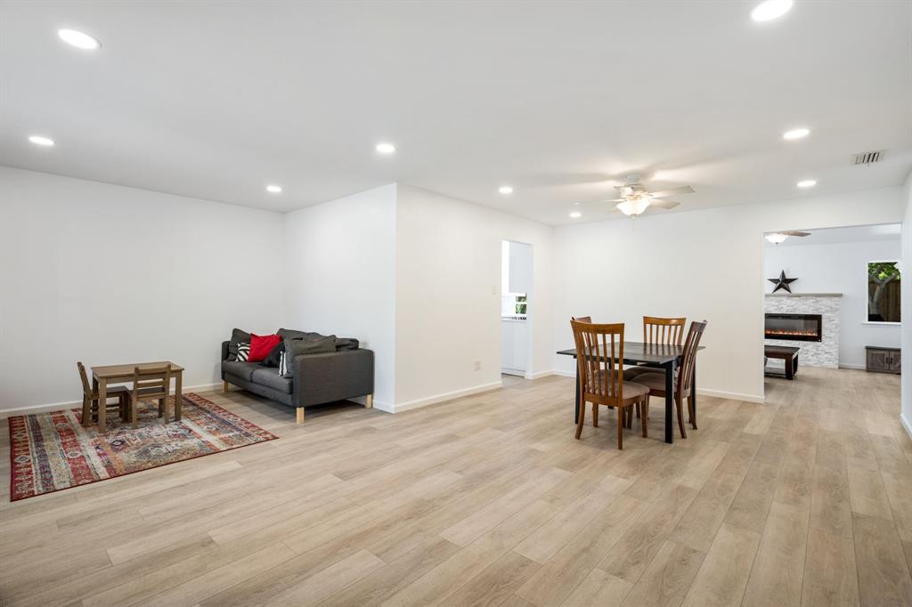 Open-concept interior featuring light wood-finish flooring, recessed lighting, and a stone-clad electric fireplace