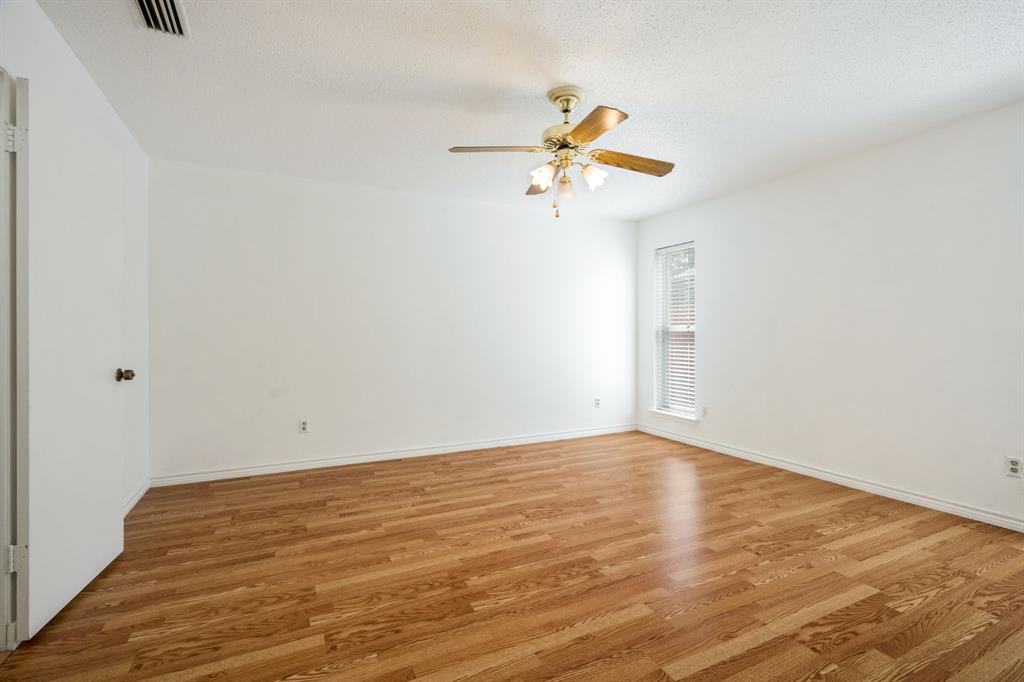 Interior room featuring wood-finish flooring, a ceiling fan with integrated light fixture, and a vertical window