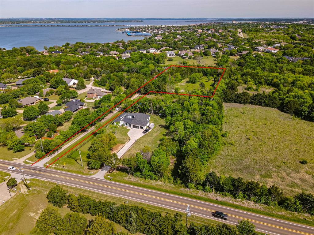 Expansive property featuring a modern residence, dedicated driveway, and established trees Expansive property featuring a modern residence, dedicated driveway, and established trees