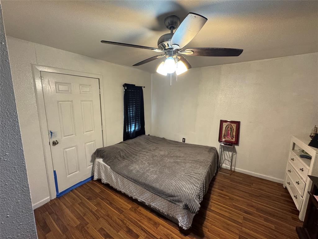 Bedroom with a textured wall, dark wood finished floors, a ceiling fan, and a textured ceiling