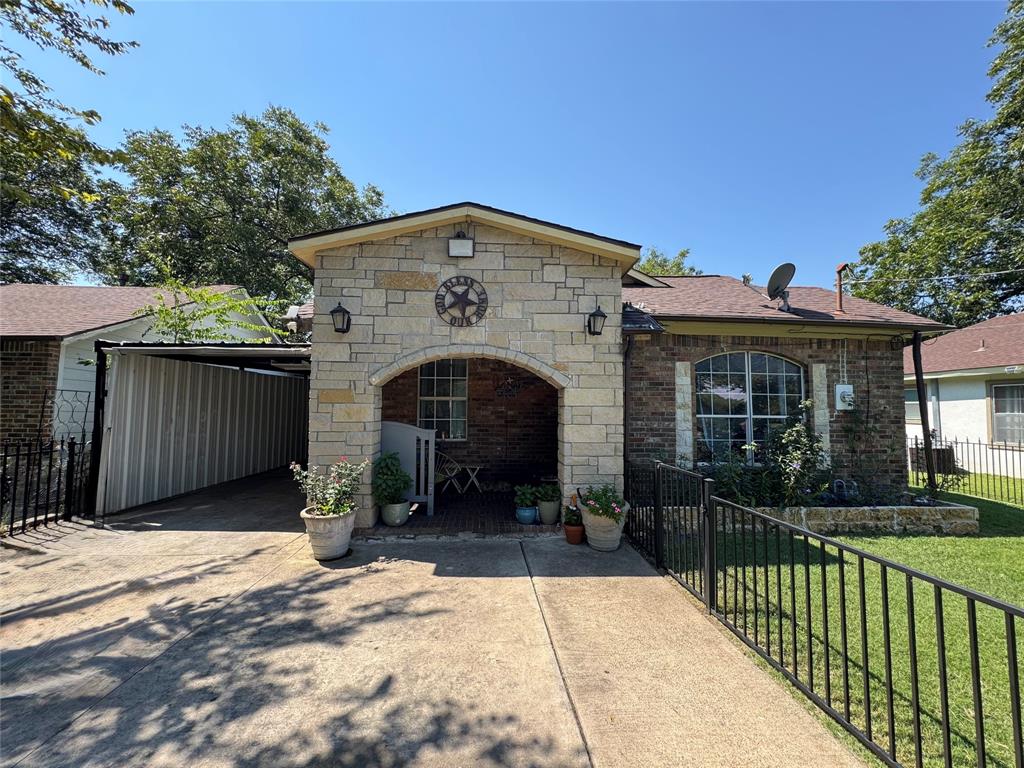 View of front of home with stone siding, concrete driveway, brick siding, and a carport
