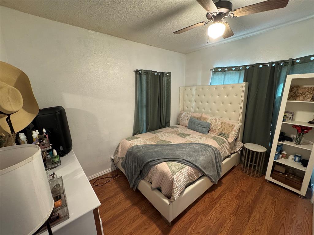 Bedroom with a textured ceiling, wood finished floors, ceiling fan, and a textured wall Bedroom with a textured ceiling, wood finished floors, ceiling fan, and a textured wall