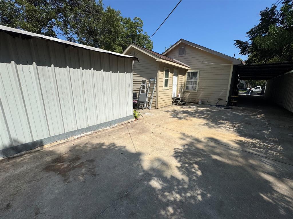 View of property exterior with a carport and concrete driveway