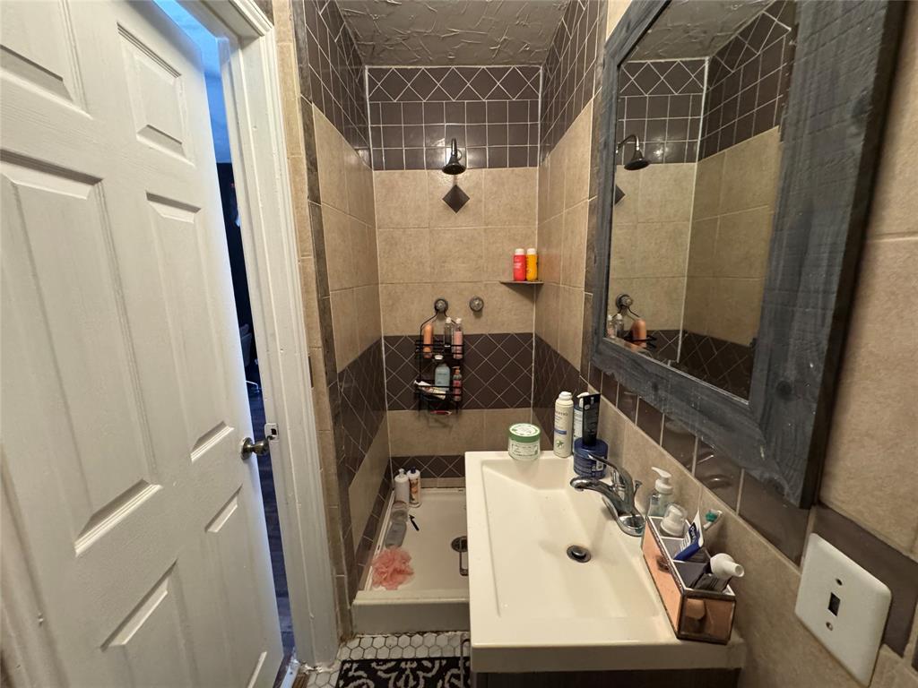 Full bathroom featuring vanity, tile walls, and tiled shower