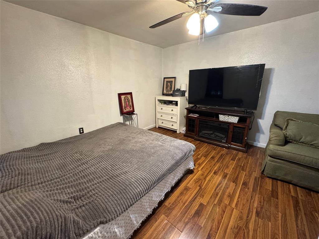 Bedroom featuring dark wood finished floors, a ceiling fan, and a textured wall Bedroom featuring dark wood finished floors, a ceiling fan, and a textured wall