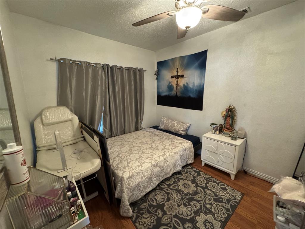 Bedroom with dark wood finished floors, a textured ceiling, ceiling fan, and a textured wall Bedroom with dark wood finished floors, a textured ceiling, ceiling fan, and a textured wall