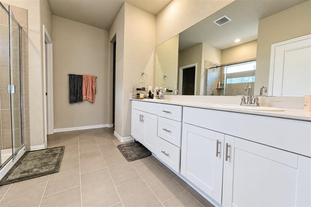 Spacious bathroom featuring a dual vanity with white cabinetry, light-toned countertops, and a large mirror