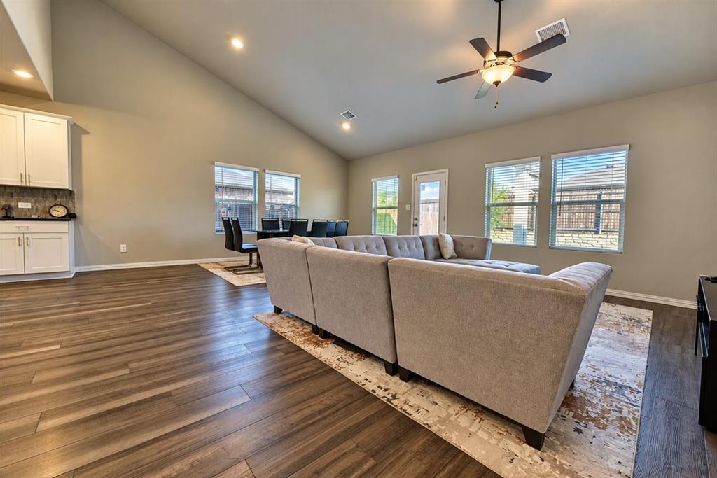 Vaulted ceilings, wood-finish flooring, recessed lighting, ceiling fan, and multiple windows with blinds