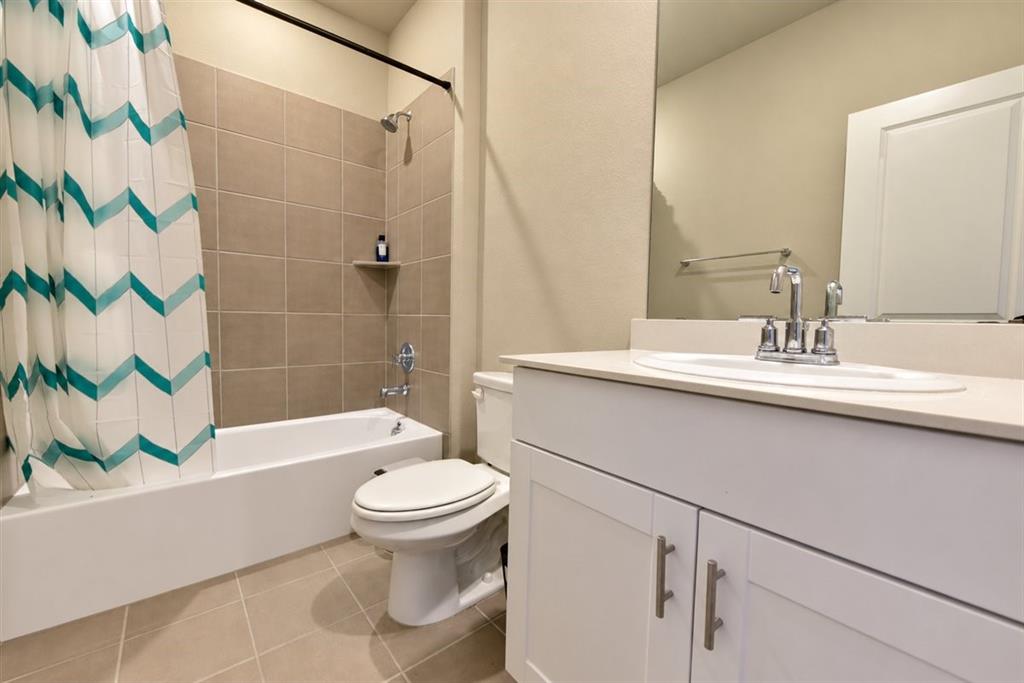 White vanity with shaker-style cabinetry, a built-in sink, and a light-toned countertop