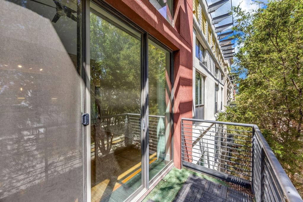 Balcony featuring sliding glass doors, metal railings, and a partial faux turf surface