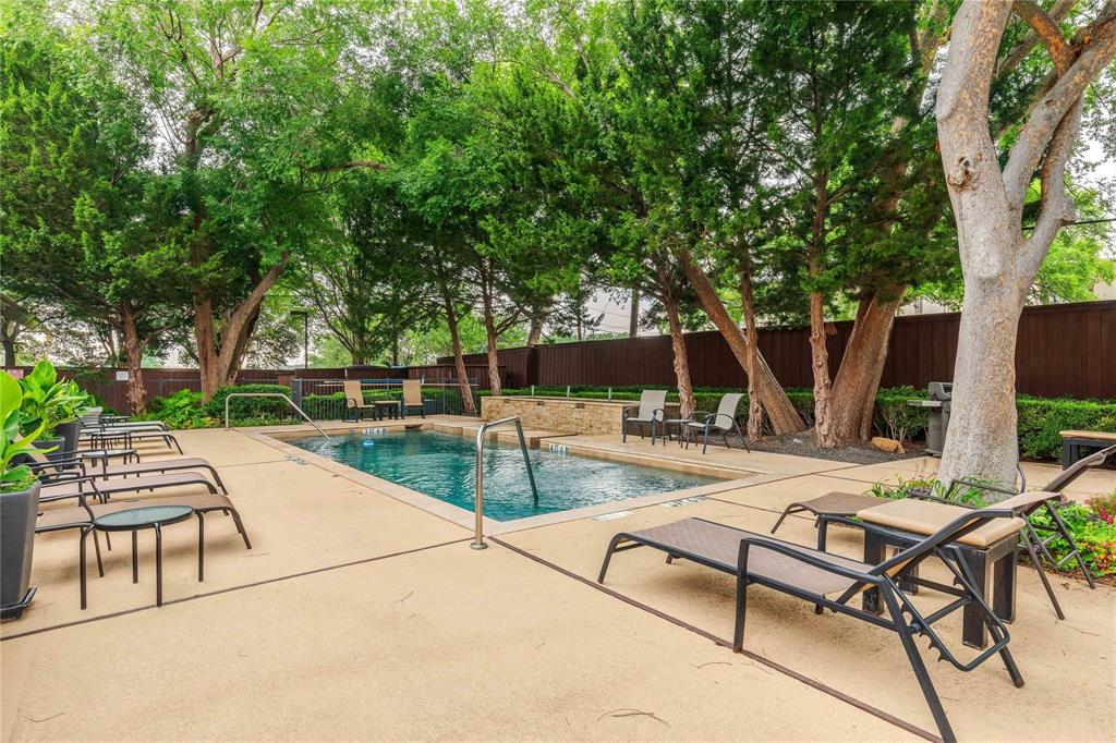 Outdoor swimming pool featuring a perimeter of mature trees and a surrounding hardscape deck