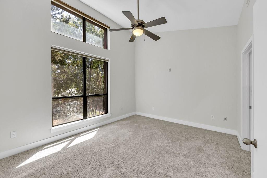 Vaulted ceiling, oversized windows, additional transom windows, ceiling fan, and light-toned carpeting