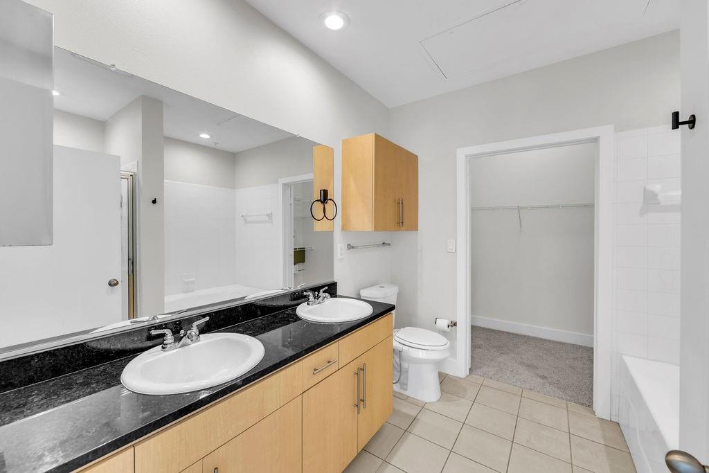 Dual vanity with under-sink cabinetry, dark countertop, and integrated sinks