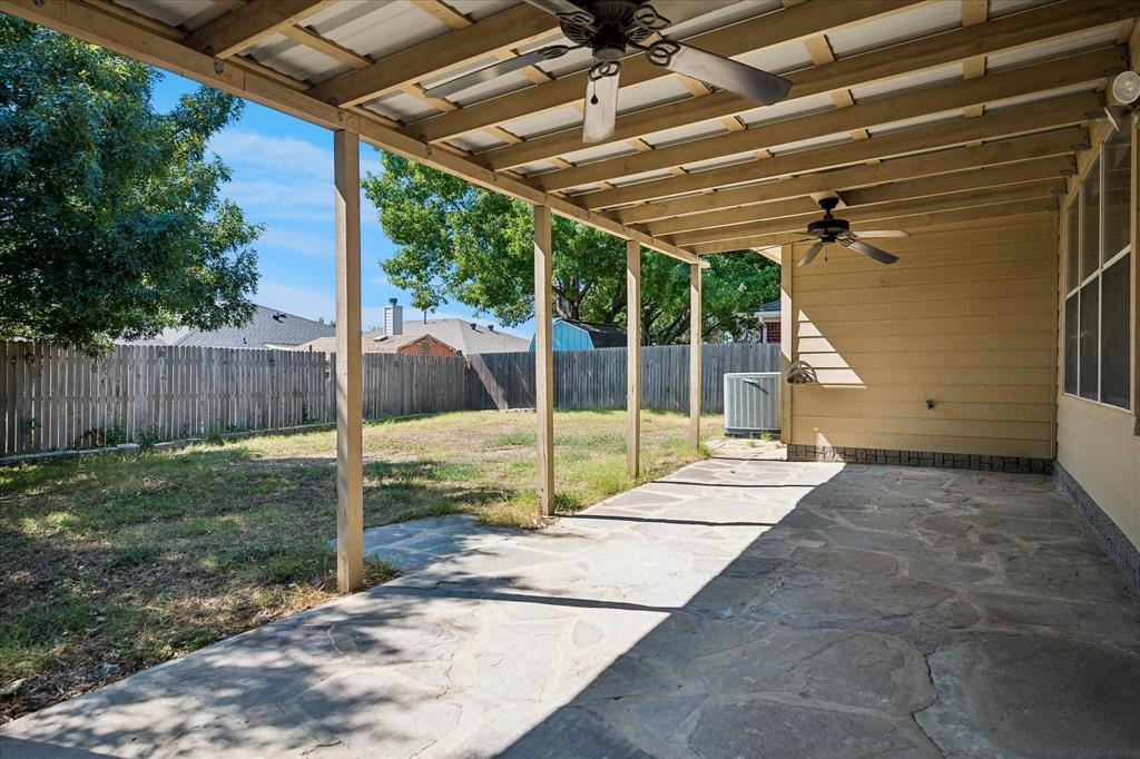Covered patio featuring flagstone flooring, two ceiling fans, and a metal roof