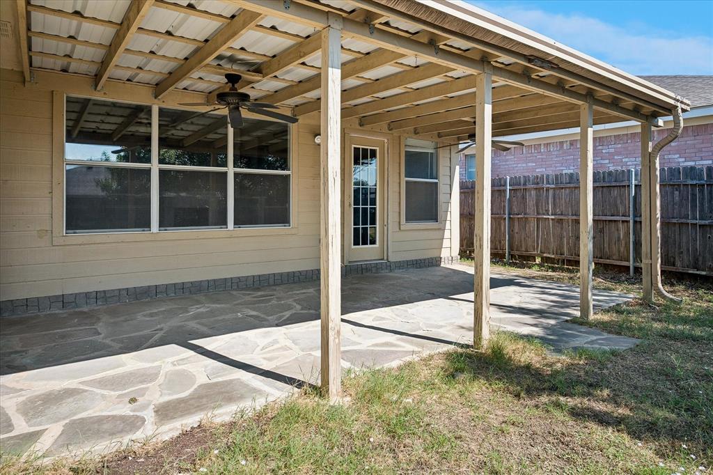 Covered patio with a metal roof and ceiling fan, featuring flagstone-style paving and direct access to the interior