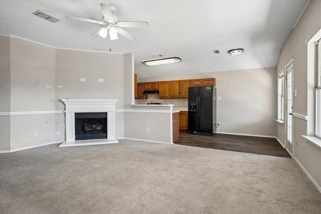 Living area with a fireplace, ceiling fan, and carpeted flooring