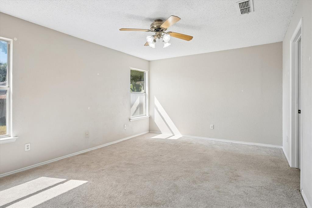 Carpeted flooring, ceiling fan with light fixture, and multiple windows