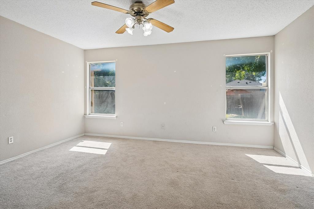 Neutral wall color, two windows, ceiling fan with light fixture, and carpeted flooring