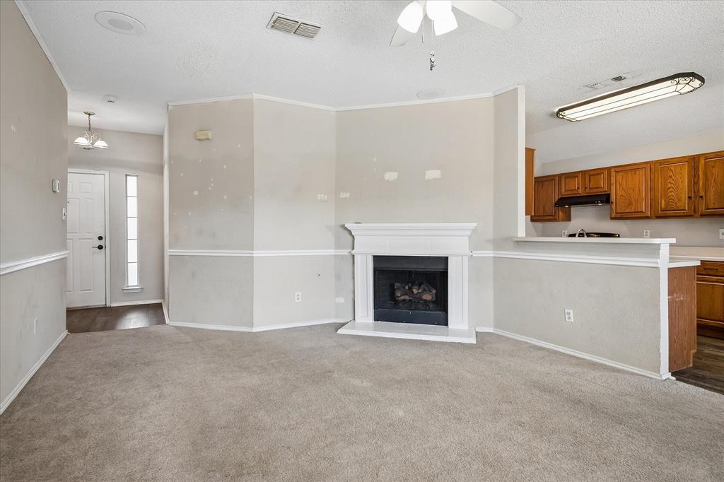 Carpeted living area with a fireplace and mantel, crown molding, and a ceiling fan