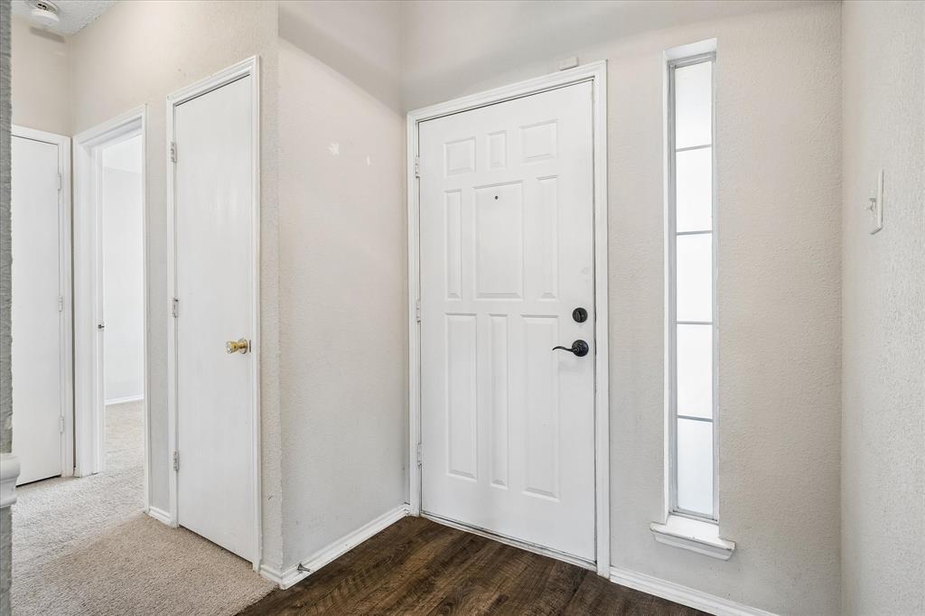 Entryway with a paneled door, vertical window, and wood-finish flooring