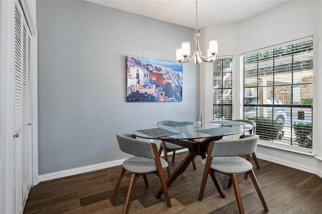 Bay window with multi-pane windows, wood-finish flooring, and multi-arm chandelier with glass shades
