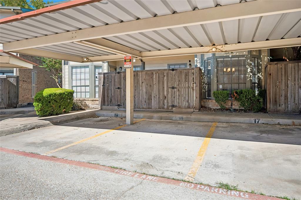 Covered parking structure with designated spaces, concrete surface, and wood privacy fencing