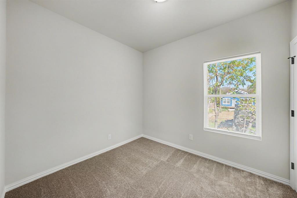 Neutral wall color, window with natural light, textured carpet, and white trim